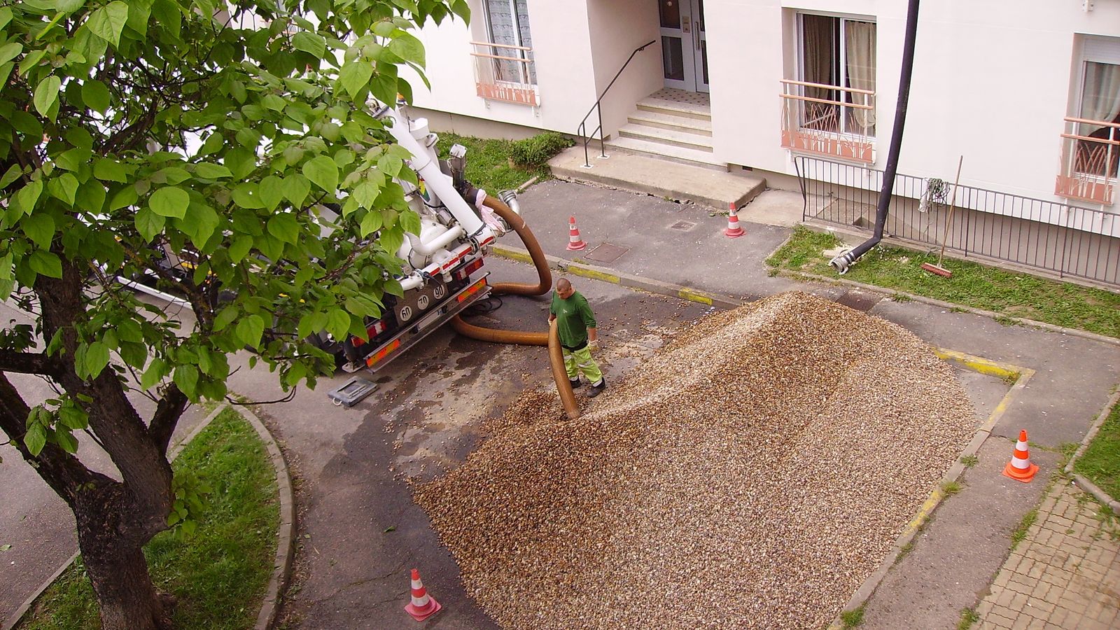 A bare plot of gravel beside a building, before any planting