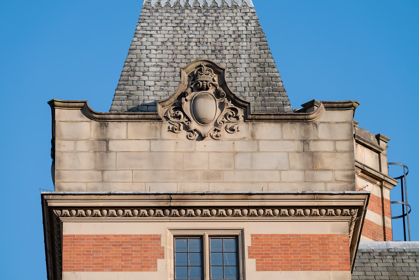 Sandstone and red-brick building with an ornate carved cartouche below a slate roof, Lincoln's Inn Fields, London