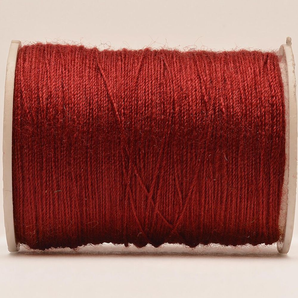 A spool of red cotton thread with the end drawn out
