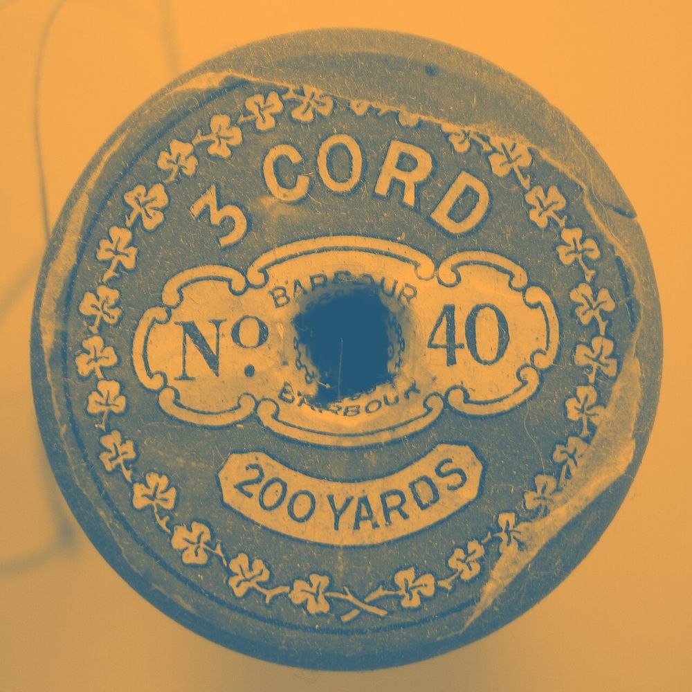 A vintage cotton thread label with numbers and a clover border